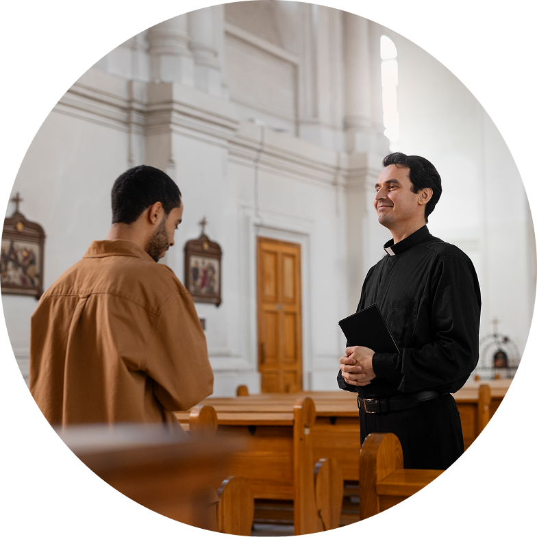 A man in a brown shirt engages with a priest holding a book inside a church, surrounded by wooden pews and religious artwork, highlighting the essence of intercultural church services.