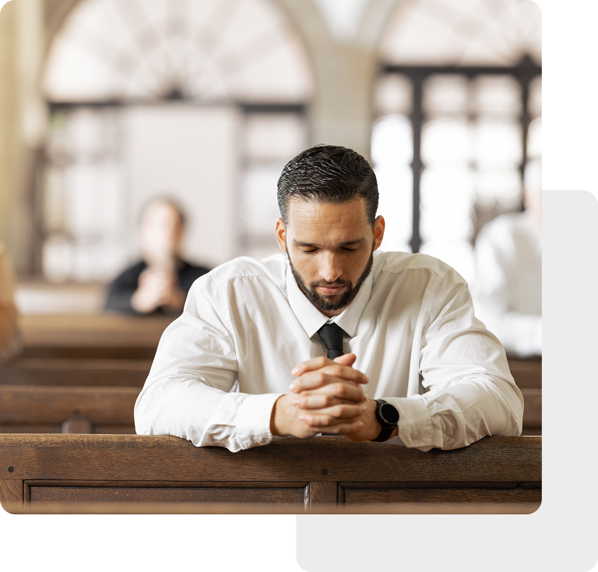 A man in a white shirt and tie sits in a pew, hands clasped, appearing contemplative. His expression reflects the welcoming spirit often found in non-denominational churches.